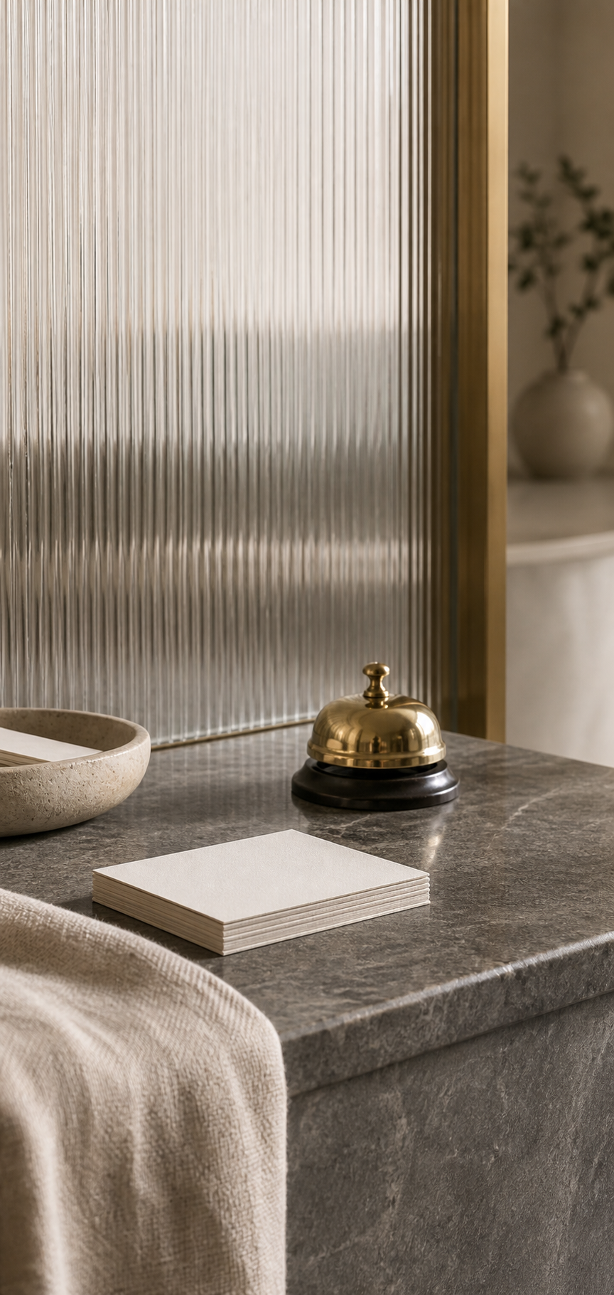 Quiet boutique clinic reception desk with a brass bell and appointment cards